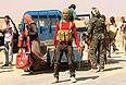 Солдаты курдской армии помогают беженцам в пути.