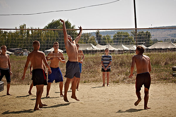 Размещенные в транзитном пункте подростки играют в волейбол.