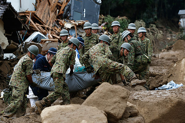 Спасатели несут найденное под завалами тело жителя Хиросимы.