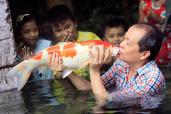 Хозяин зоопарка в Маниле целует японского карпа (Кои). Дети, кажется, одобряют.