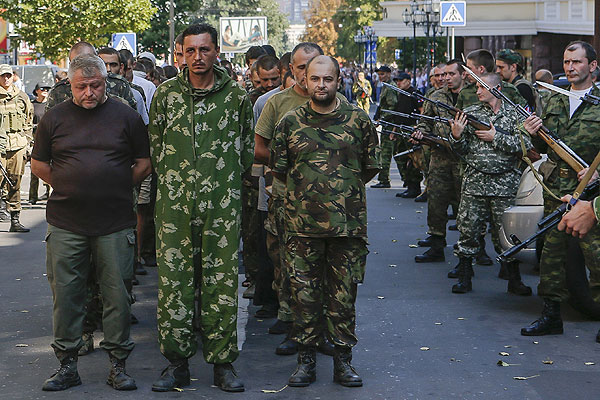 Пленные военнослужащие украинской армии проходят в центре города в сопровождении вооруженного конвоя.