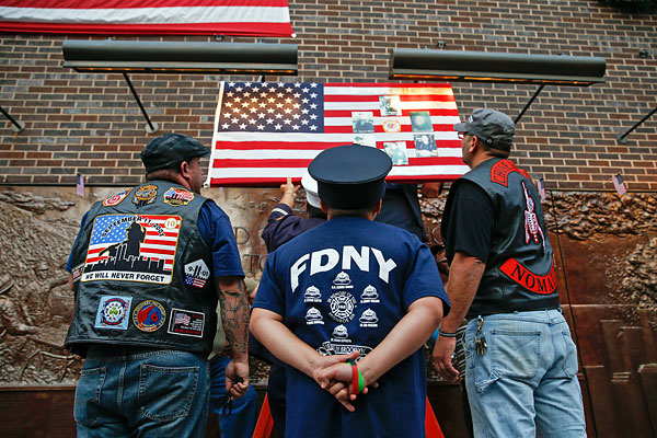 Пожарные одними из первых прибыли на место взрывов башен-близнецов. 341 пожарный погиб в горящих зданиях. На этой фотографии мужчины вывешивают американский флаг на здание Пожарного департамента Нью-Йорка в преддверии 13-й годовщины терактов.