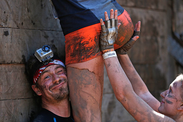 Участники соревнования на выносливость Tough Mudder преодолевают препятствие.