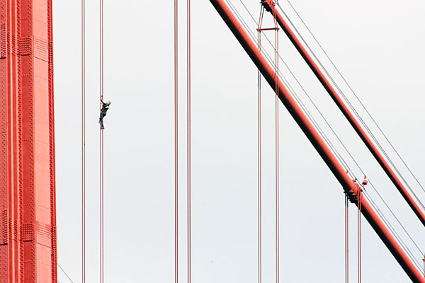 Скалолаз взбирается на мост над рекой Тахо в Лиссабоне, Португалия. Август 2007.