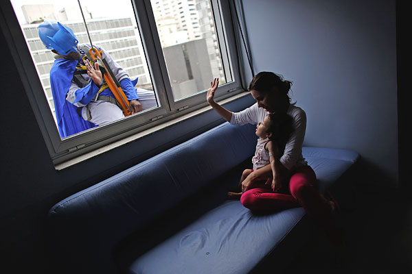 Мужчина в костюме Бэтмена моет окна детской больницы в Сан-Паулу.