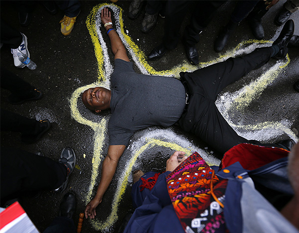 Мужчина изображает жертву во время акции протеста против полицейского насилия в Фергюсоне.