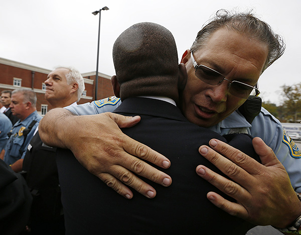 Полицейский обнимается с лидером религиозных активистов во время акции протеста против полицейского насилия в Фергюсоне.