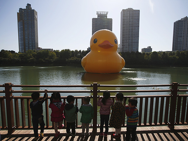 Воспитанники детского сада наблюдают за проплывающей по реке огромной фигурой резинового утенка. Датский художник Флорентин Хофман сделал его для промо мероприятий Lotte World Tower в Сеуле.