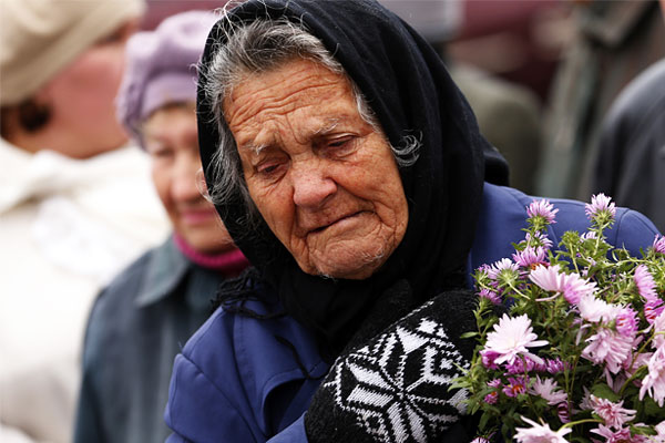 Пожилая женщина во время панихиды.