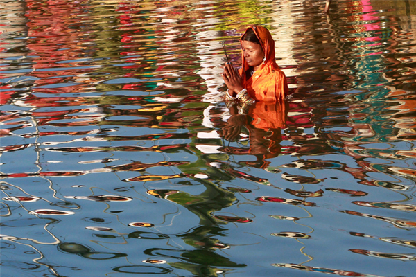 Верующая приветствует Солнце пением мантры, сложив руки в молитве в городе Агартала.