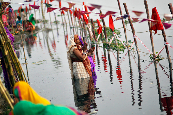 Женщины поклоняются богу Солнца в водах реки Ямуна.