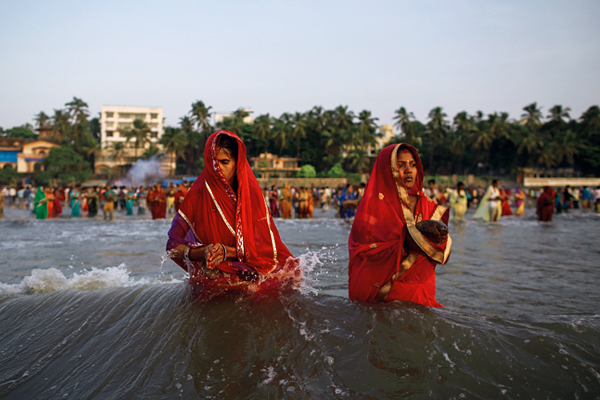 Индийские женщины во время молитвы заходящему Солнцу в Мумбаи.