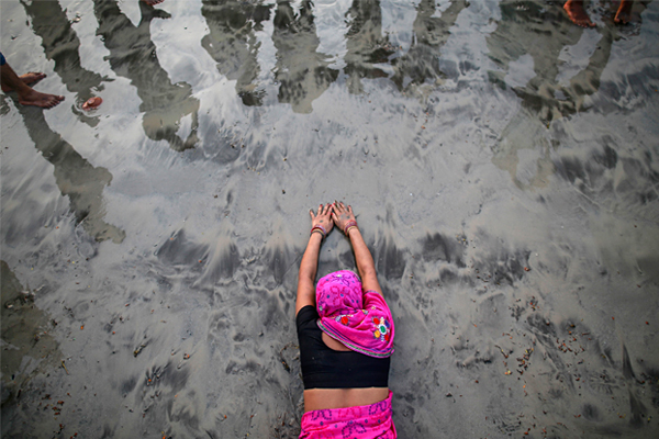 Женщина молится заходящему Солнцу во время праздника на побережье Аравийского моря в Мумбаи.