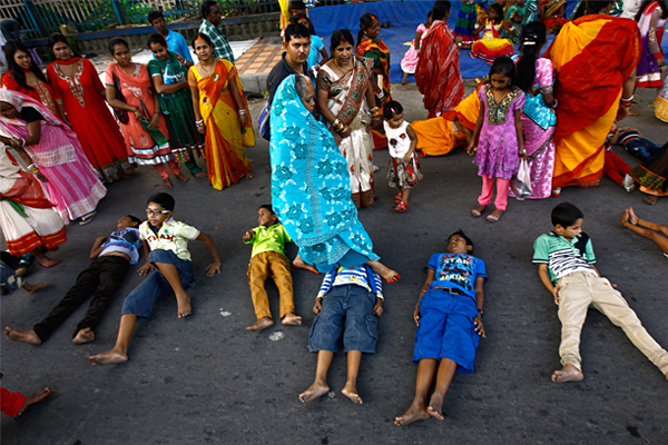 Женщина перешагивает через ребенка, тем самым совершая ритуал его благословения на фестивале в Калькутте.