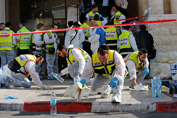 Добровольцы израильской общественной организации ЗАКА отмывают кровь на месте нападения.