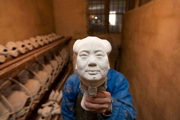 Работник завода демонстрирует голову статуи покойного председателя КНР Мао Цзэдуна, провинция Хунань, Китай