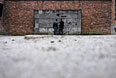 Посетители Государственного музея Аушвиц-Биркенау у воссозданной "стены смерти", где расстреливали узников после допросов