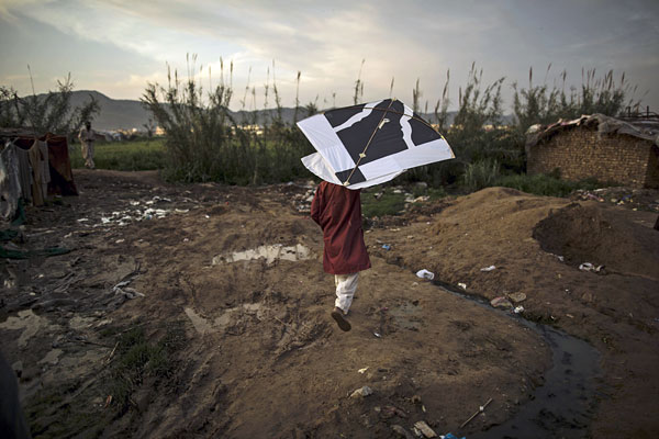 Ребенок запускает воздушного змея в трущобах Исламабада. Пакистан.