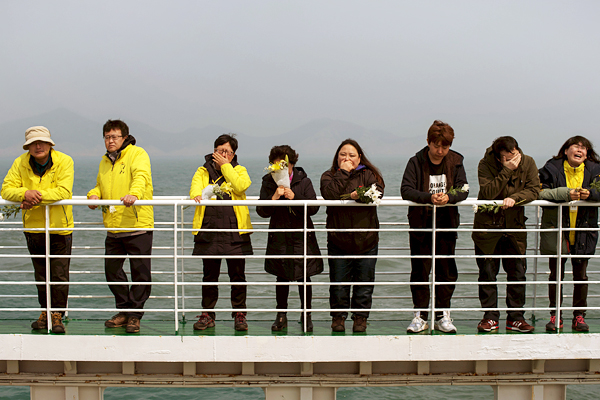 Родные оплакивают погибших и бросают цветы в море в знак памяти о жертвах катастрофы