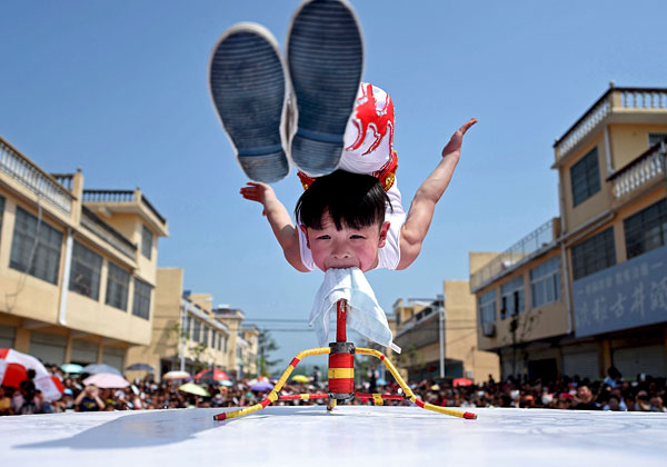 Шестилетний акробат выступает на открытии туристического фестиваля в Бочжоу. Китай.