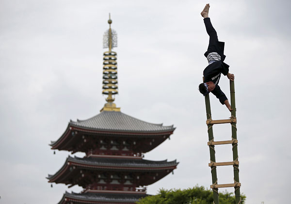 Акробат выполняет трюк во время памятных мероприятий, посвященных погибшим при исполнении своих обязанностей пожарным. Токио, Япония.