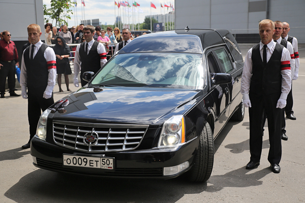 Сотрудники ритуальной службы сопровождают катафалк с телом певицы