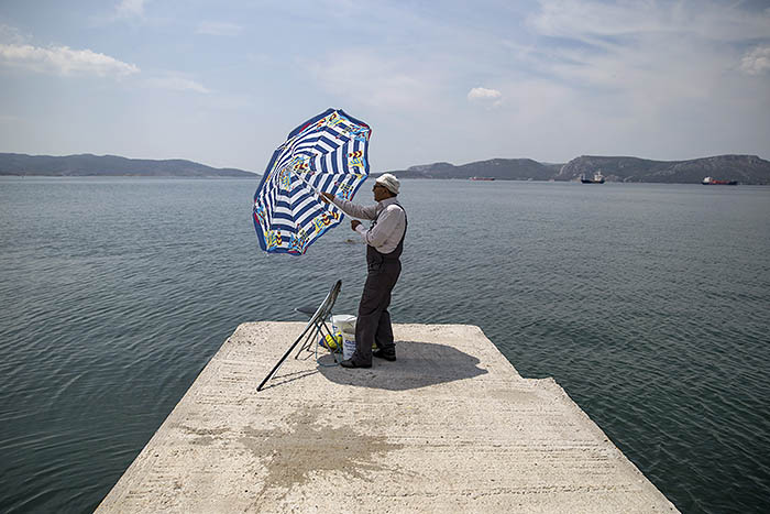 Мужчина прячется от солнца на побережье Греции