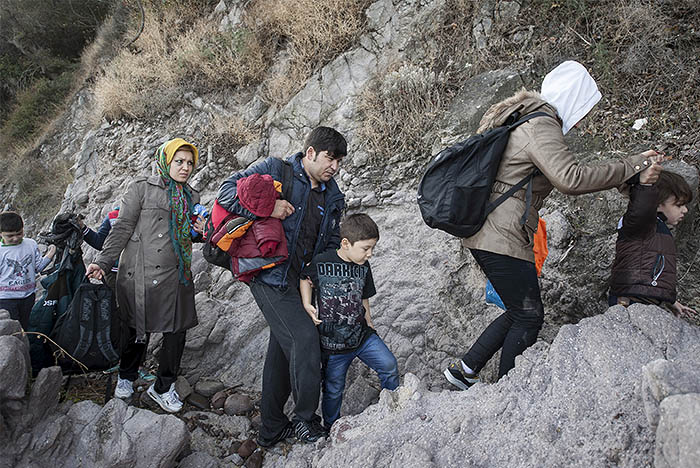 Беженцы из Афганистана поднимаются по скалистому пляжу спустя несколько минут после прибытия на лодке на греческий остров Лесбос