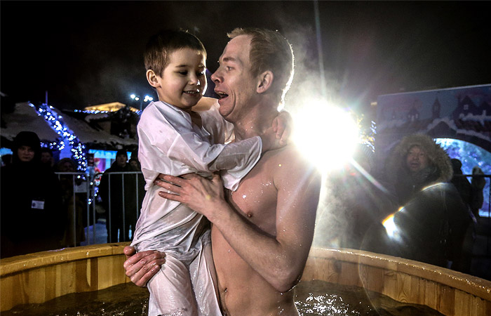 Отец с ребенком во время крещенских купаний в купели на Площади Революции