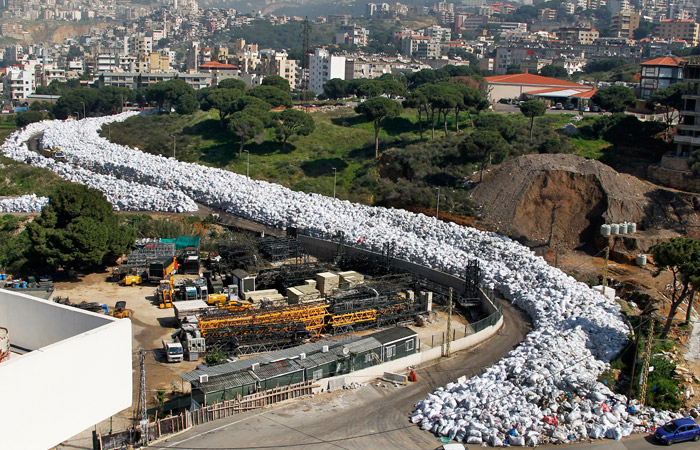 Извилистая “река мусора” протянулась вдоль улицы Эль-Джудейда на северо-западе Бейрута. Уборка отходов в столице, где проживают два миллиона человек, застопорилась в июле после закрытия временного мусорного полигона. Мусор накапливался на улицах города, а теперь его собирают и готовят для утилизации.