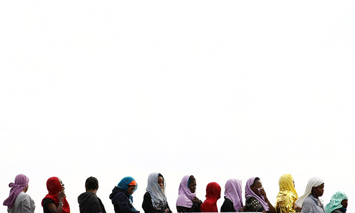 Мигранты, спасенные в Средиземном море сходят с корабля военно-морских сил Италии в сицилийском порту Аугуста