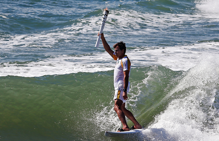 Бразильский серфер Карлос Бурле принимает участие в эстафете Олимпийского огня в Ипожуке, штат Пернамбуку