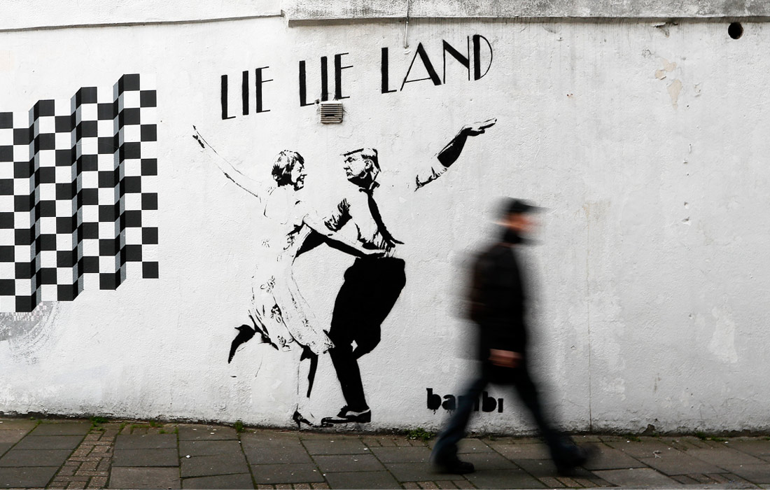 В Лондоне появилось новое граффити художника Bambi, которое пародирует постер к знаменитому фильму "Ла-Ла Ленд". Уличный художник изобразил президента США Дональда Трампа в паре с премьер-министром Великобритании Терезой Мэй.