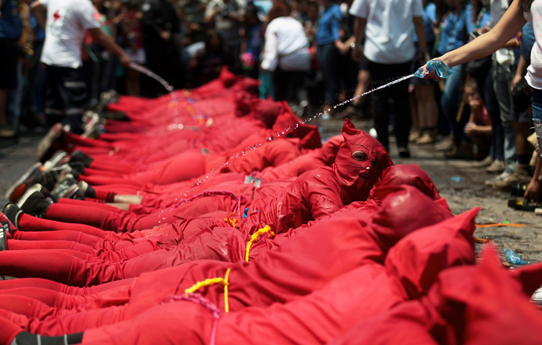 Верующих в масках дьявола обливают водой по местной традиции в день начала Страстной недели в Тексистепеке, Сальвадор