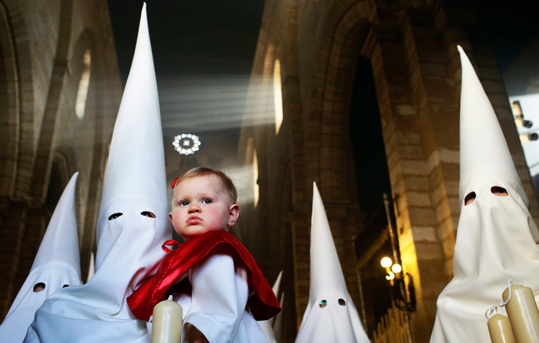 Кающиеся грешники из братства "La Borriquita" принимают участие в религиозном шествии в Кордове, Испания