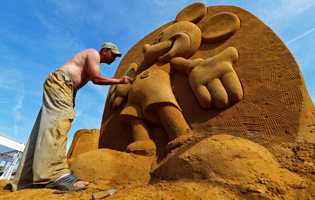 В бельгийском городе Остенде открылся ежегодный фестиваль песчаных скульптур, тема которого в этом году звучит как "Disney Sand Magic". На фото: скульптор из России Константин Кузярин работает над фигурой Микки Мауса.