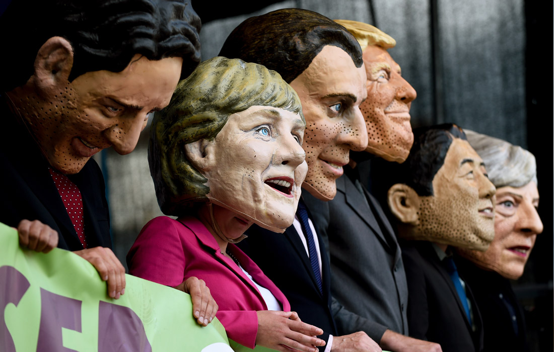 Участники акций протеста против саммита G20 в масках с изображением лидеров стран "двадцатки"