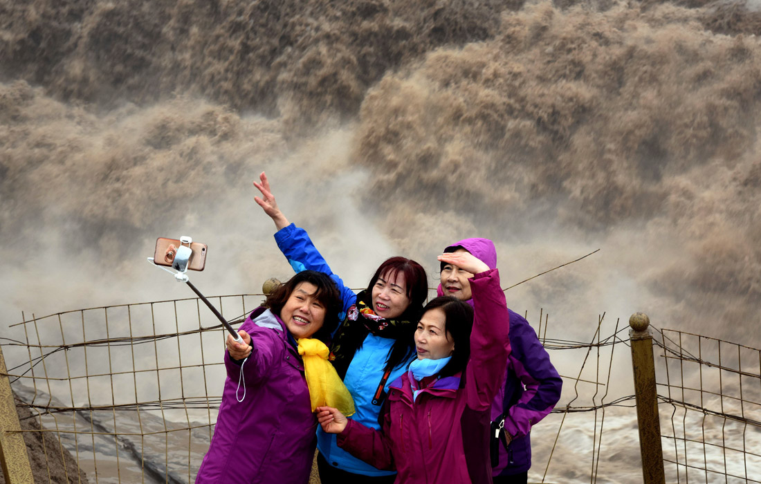 Туристы у второго по величине водопада Китая Хукоу. Его высота составляет 20 метров, а ширина 250.