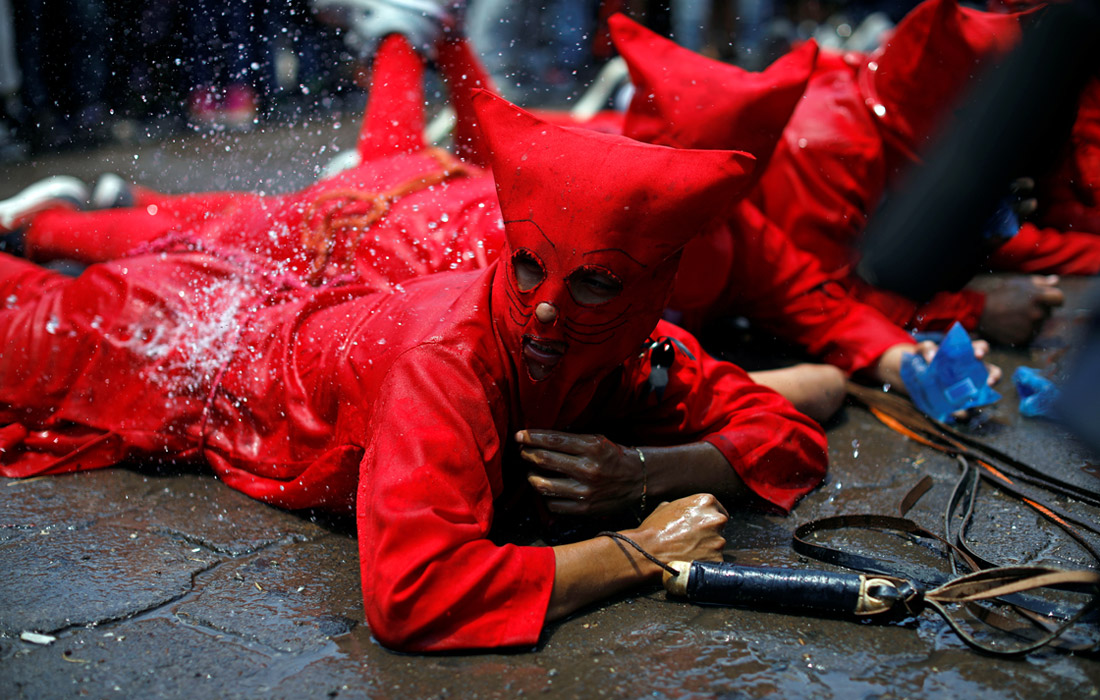 Верующих в масках дьявола обливают водой по местной традиции в день начала Страстной недели в Тексистепеке, Сальвадор