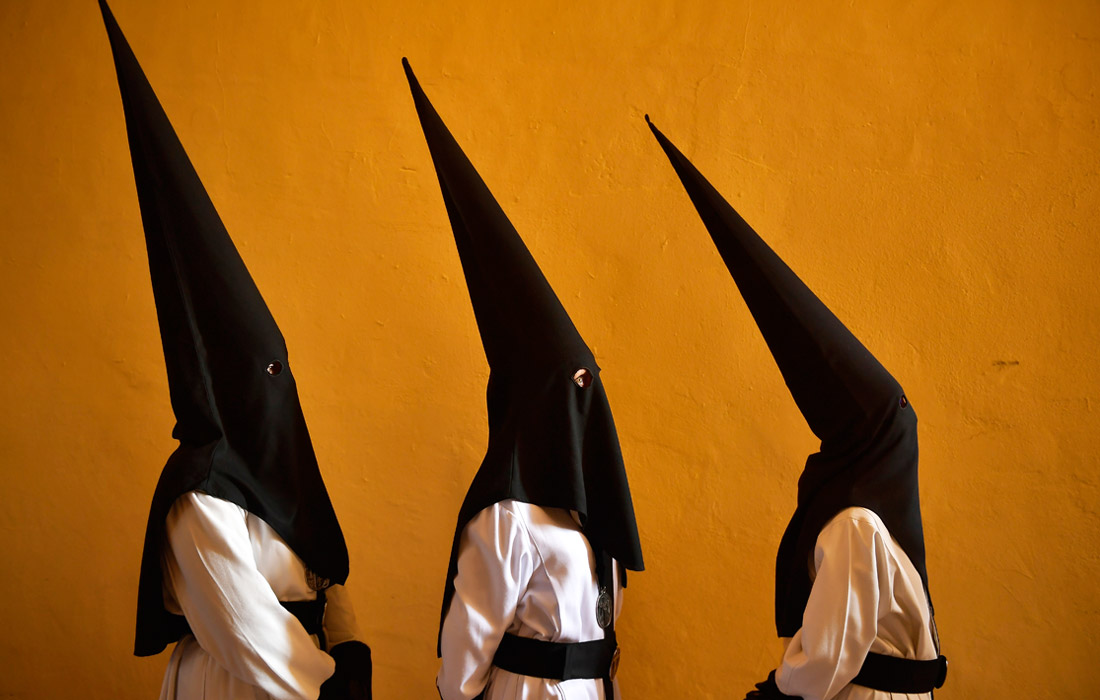 Кающиеся грешники из братства "Exaltacion de La Santa Cruz" принимают участие в религиозном шествии в Сарагосе, Испания