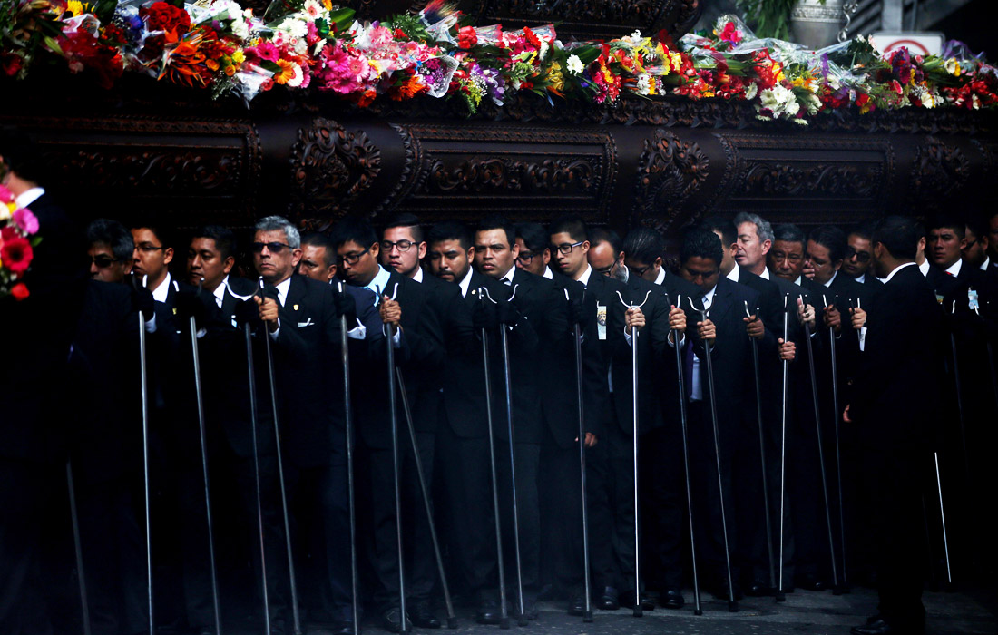 Десятки верующих несут платформу с изображением Иисуса Христа во время процессии в центре Гватемалы