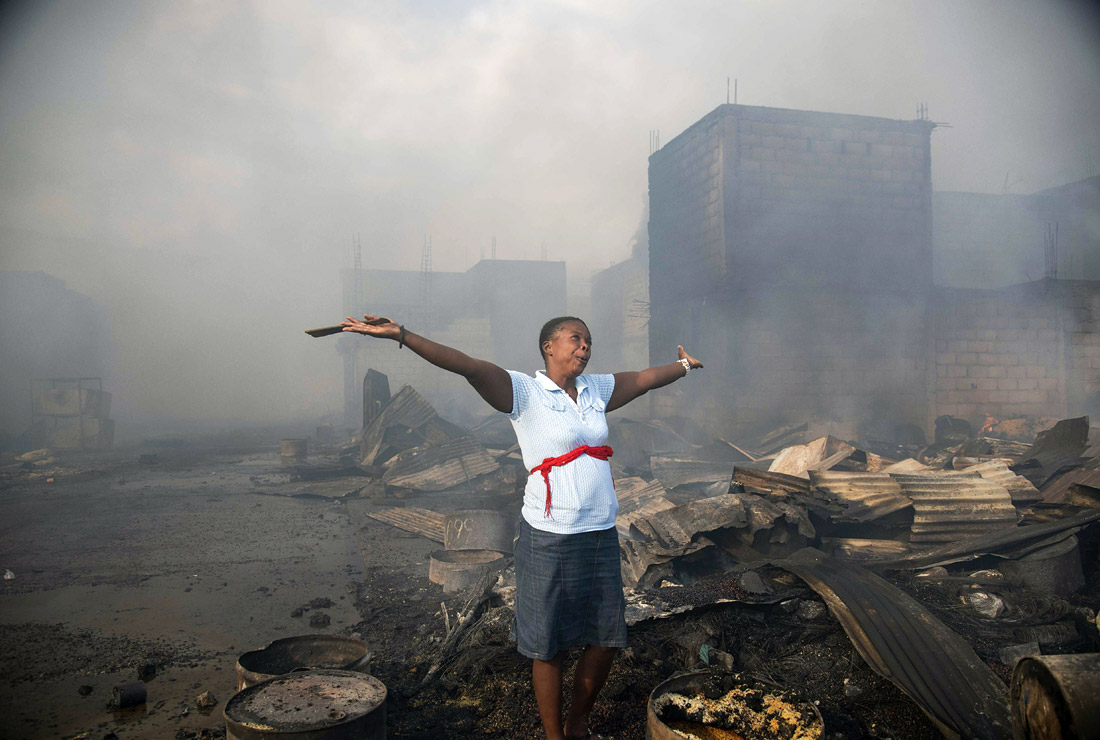Женщина молится среди обломков после пожара на одном из крупнейших рынков Меркадо дель Пуэрто в Порт-о-Пренсе