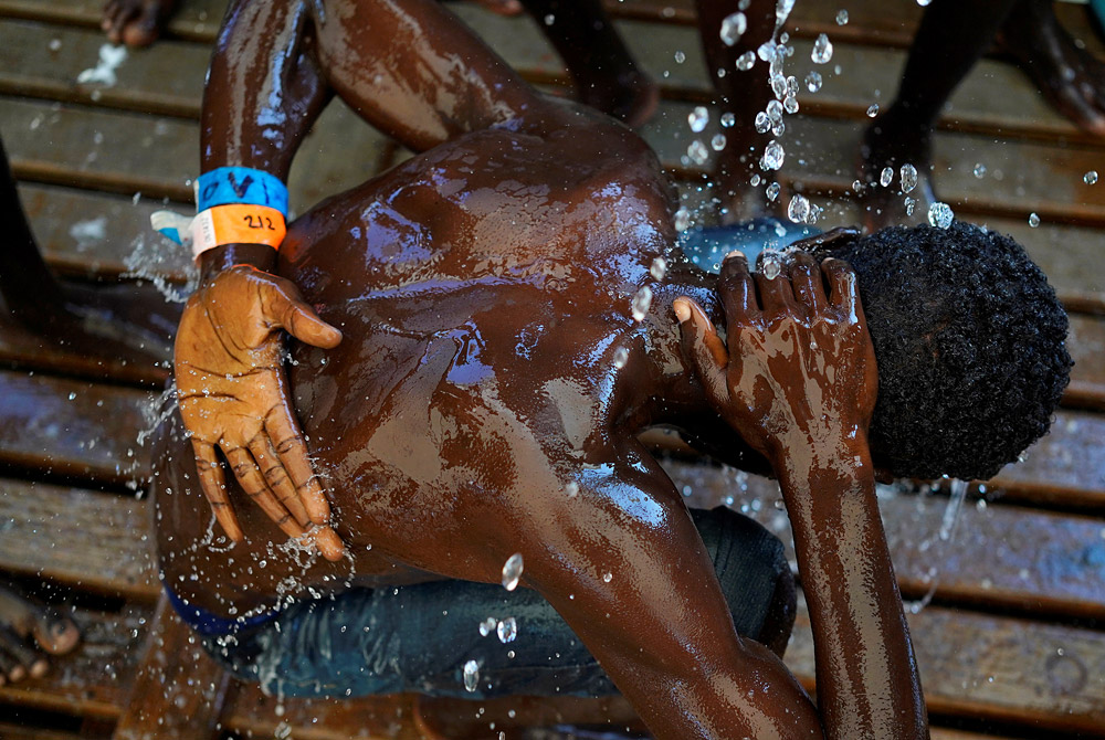 Мигрант принимает душ на борту спасательного судна Proactiva Open Arms в Средиземном море