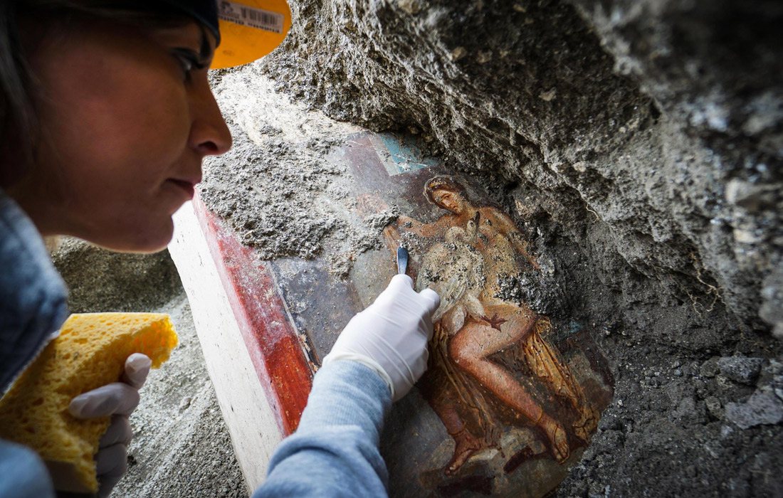 Археолог работает над фреской "Леда и лебедь", обнаруженной во время раскопок на участке Regio V в Помпеях