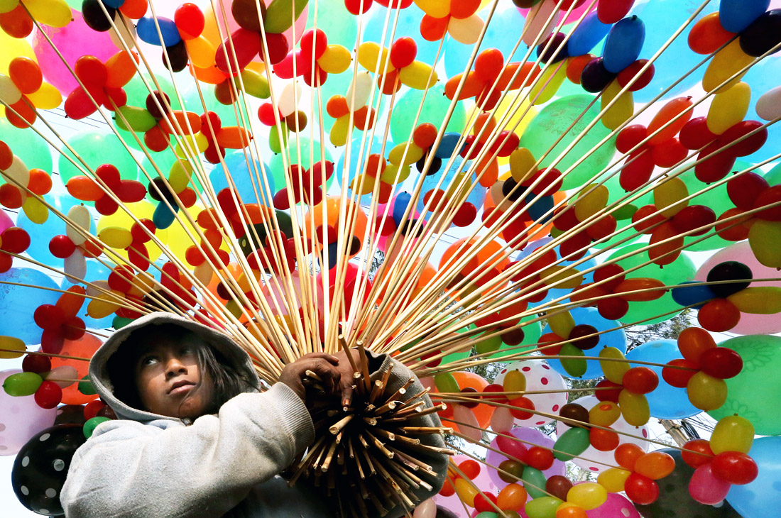 Ребенок продает воздушные шары на обочине дороги в Бхопале. Индия.
