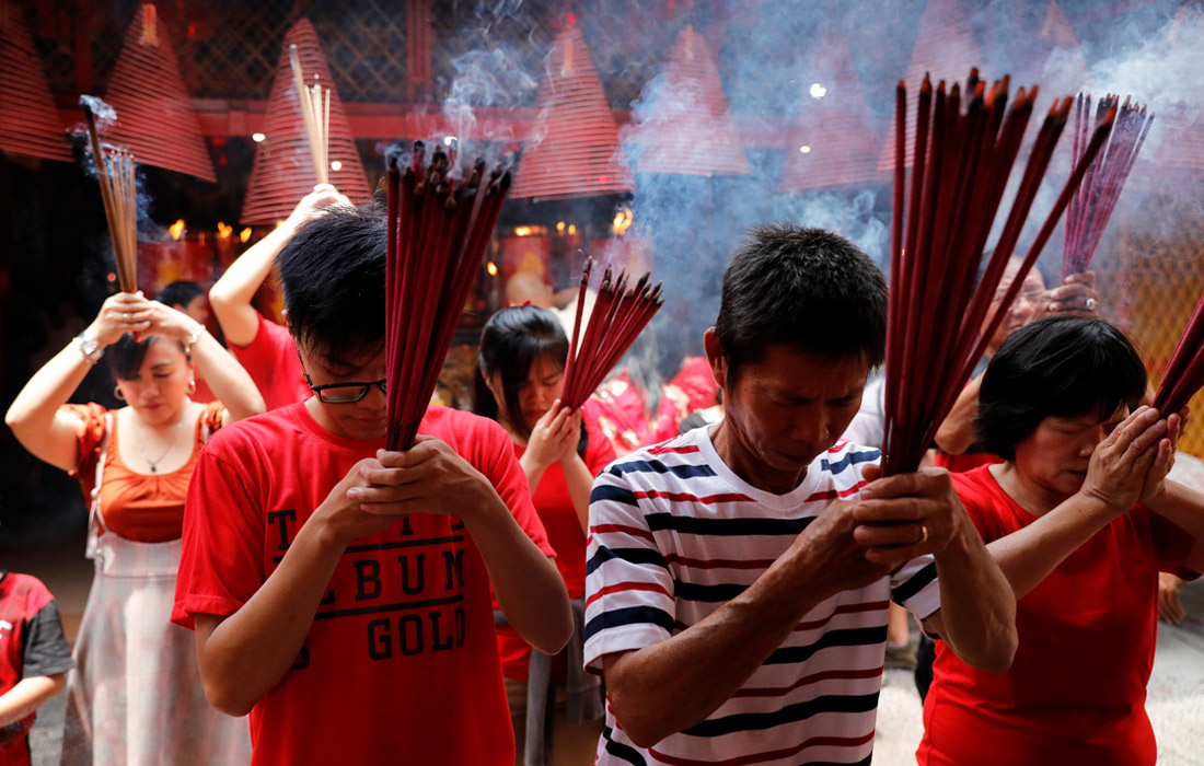 Верующие зажигают ароматические палочки во время молитвы в храме в Джакарте, Индонезия