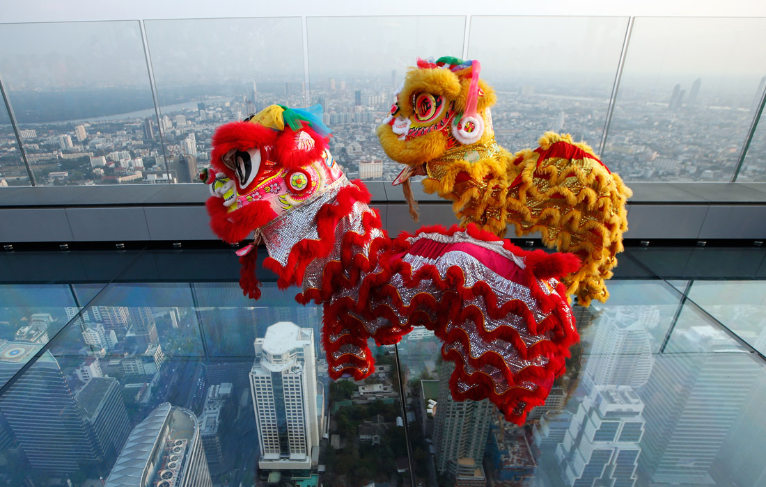 Исполнители танца льва на стеклянной палубе небоскреба Маханакхон в Тайланде