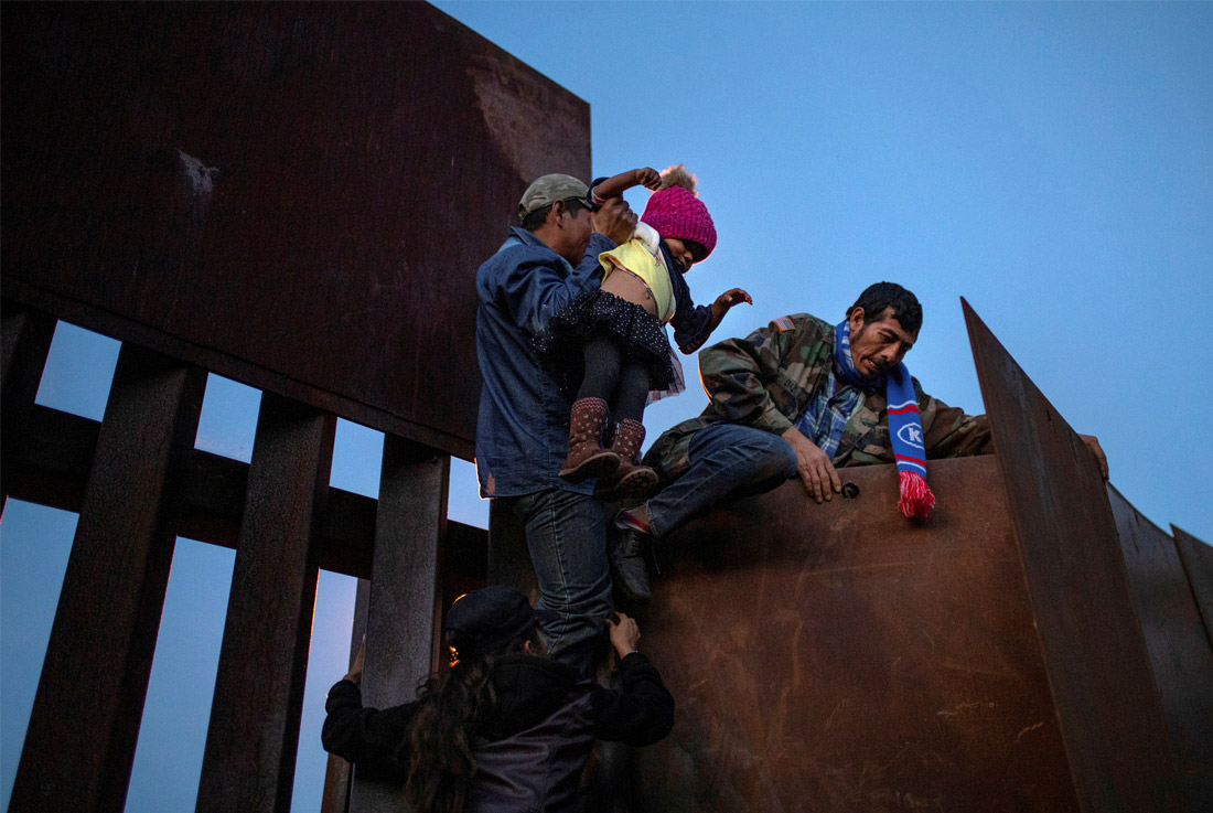 Мигранты перелезают через границу в районе города Тихуана, Мексика. 2 декабря 2018 года.