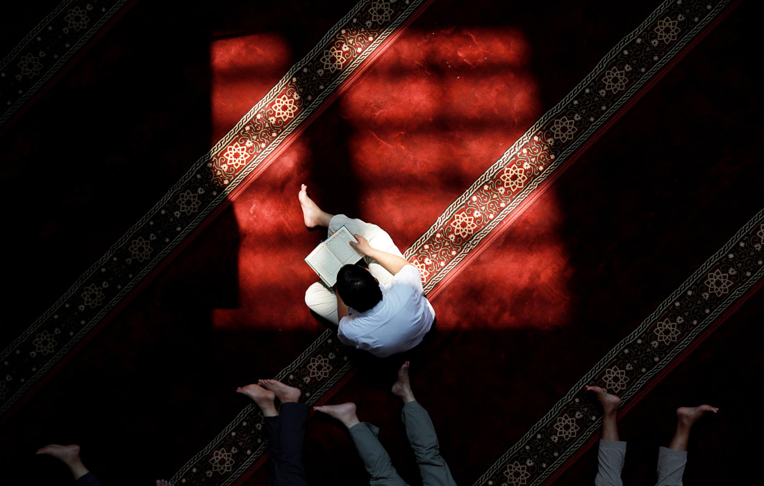 Мужчина читает Коран в мечети города Джакарта, Индонезия