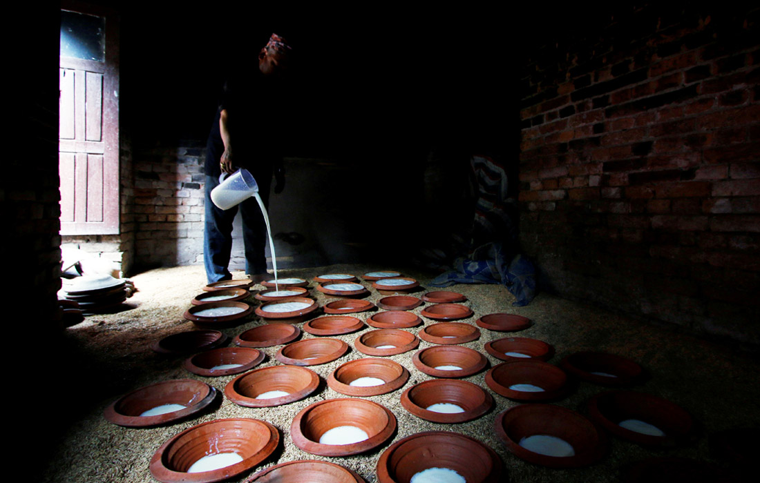 Мужчина разливает йогурт в глиняные горшки в Бхактапуре, Непал